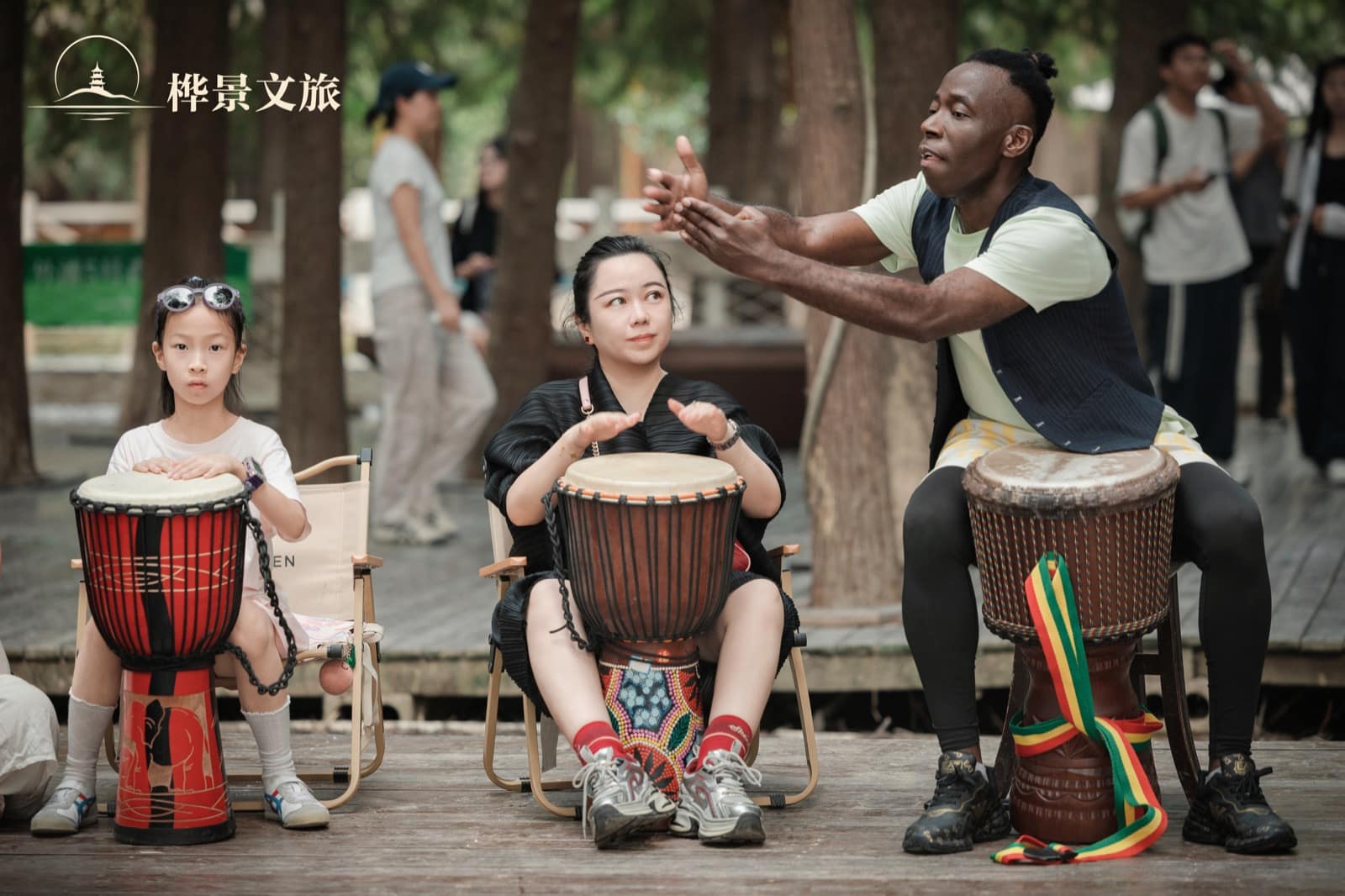 Children and adults seated with African drums during the Qingshan Lake activity.