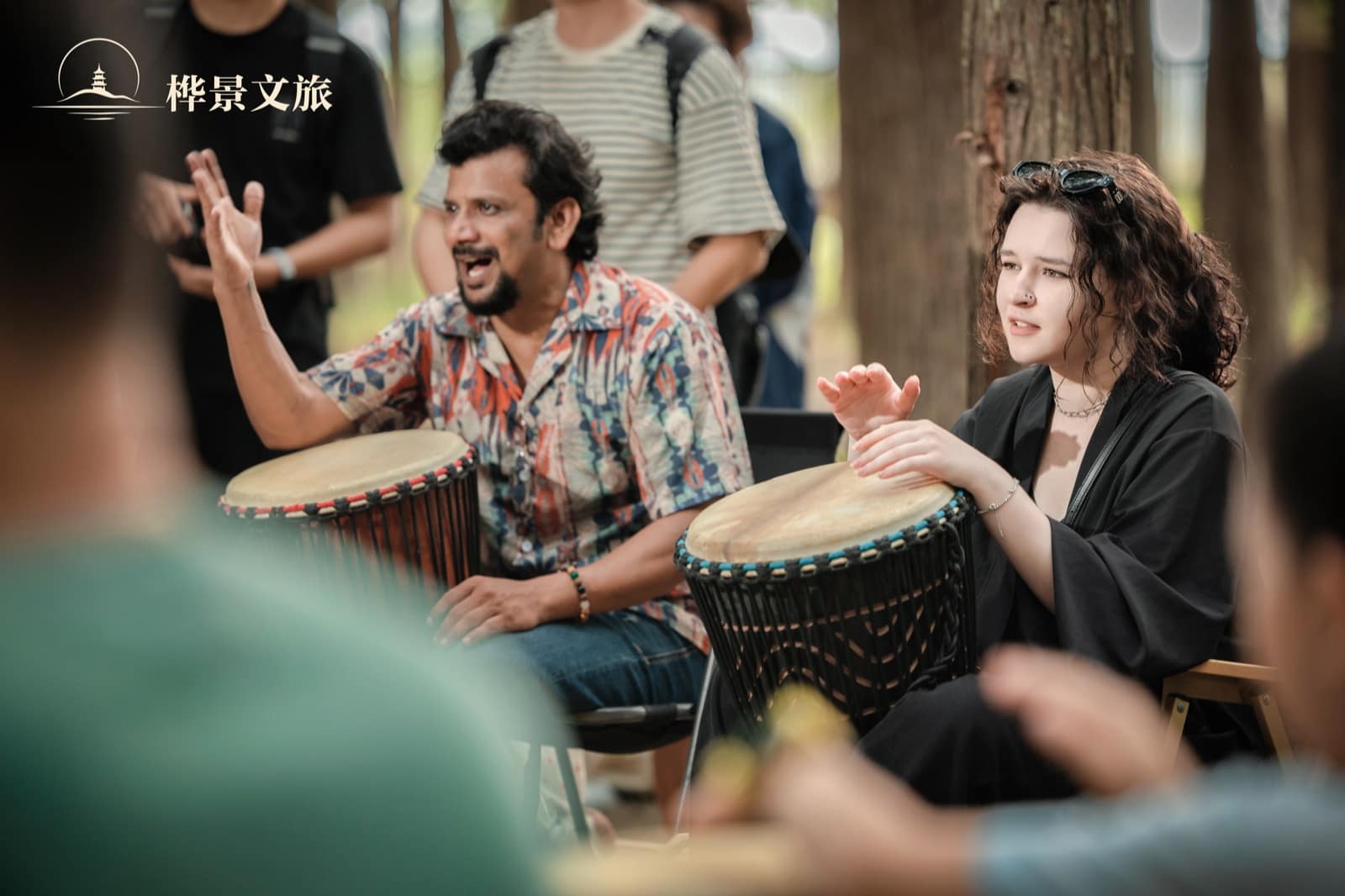 Two participants smiling as they play hand drums