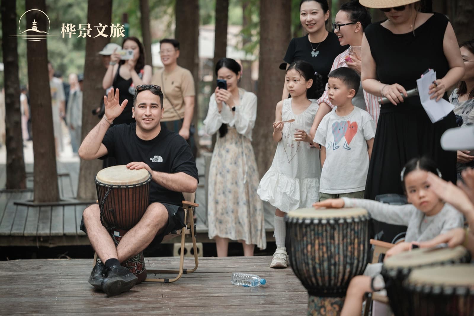 An adult and children taking part in the outdoor drum circle